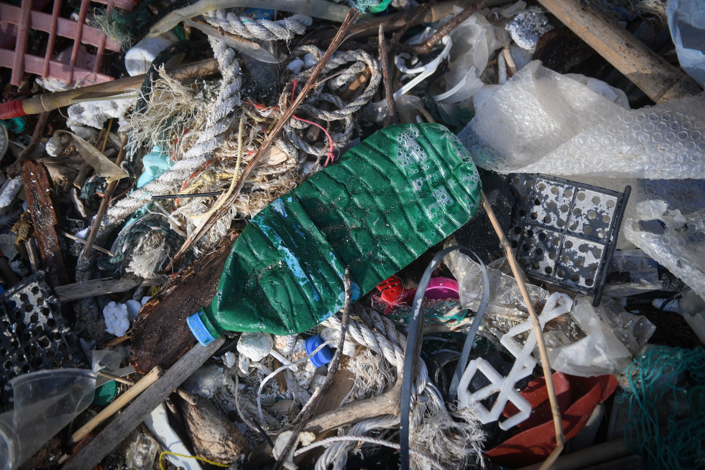 A close-up of a pile of garbage, including a plastic beverage bottle, bubble wrap, rope, and string.