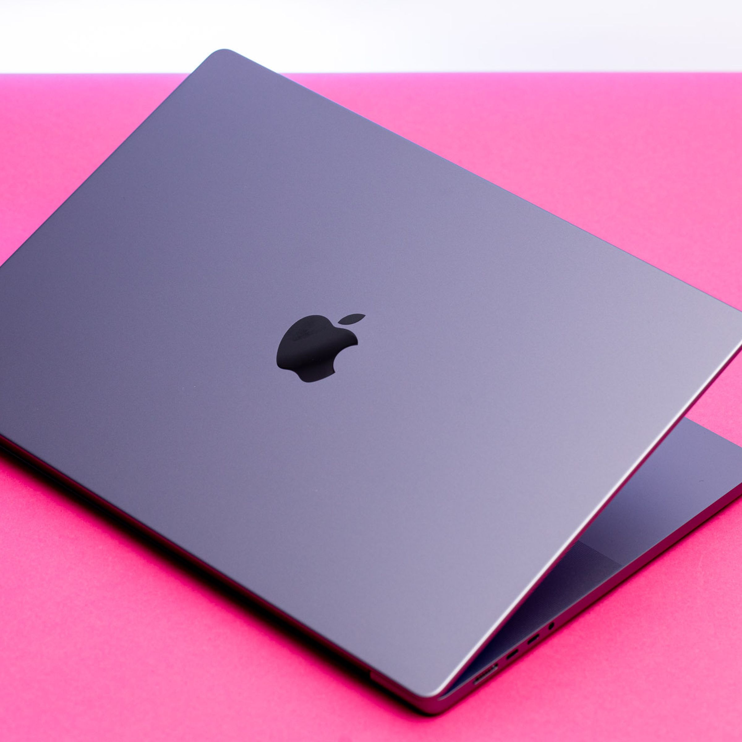 A photo showing a MacBook on a pink background