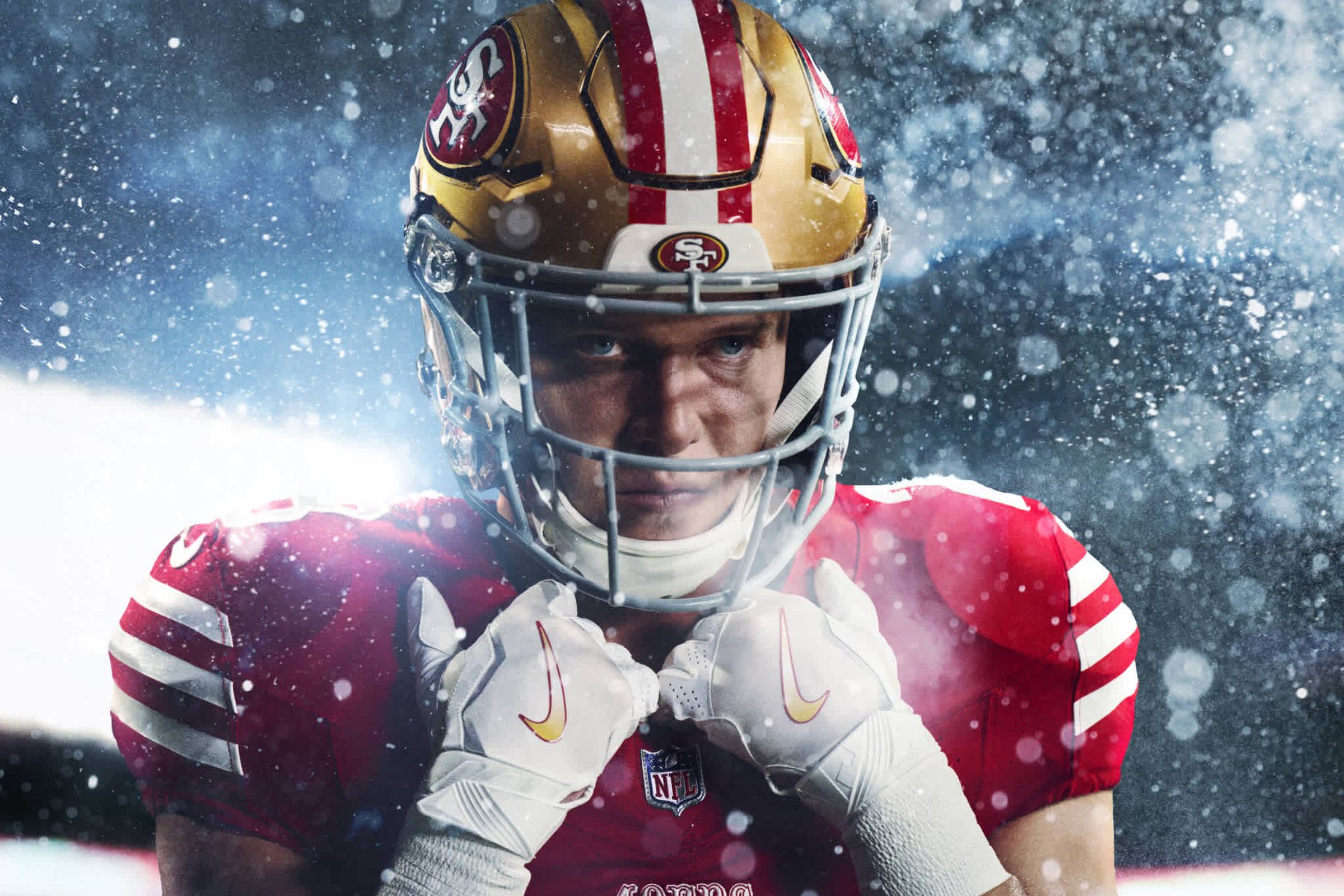A football player holding his pads, wearing a 49ers uniform.