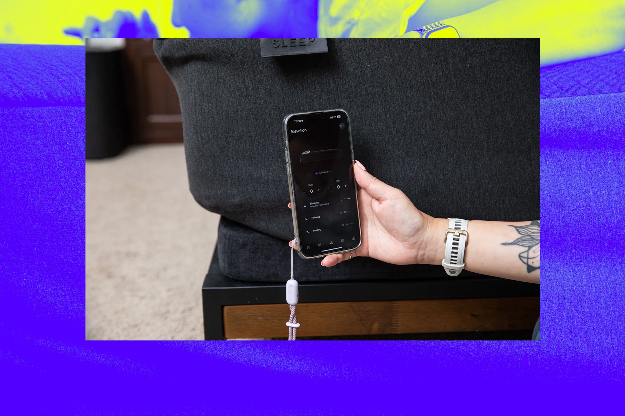 A photo of a phone controlling a bed, on top of a Vergecast background.